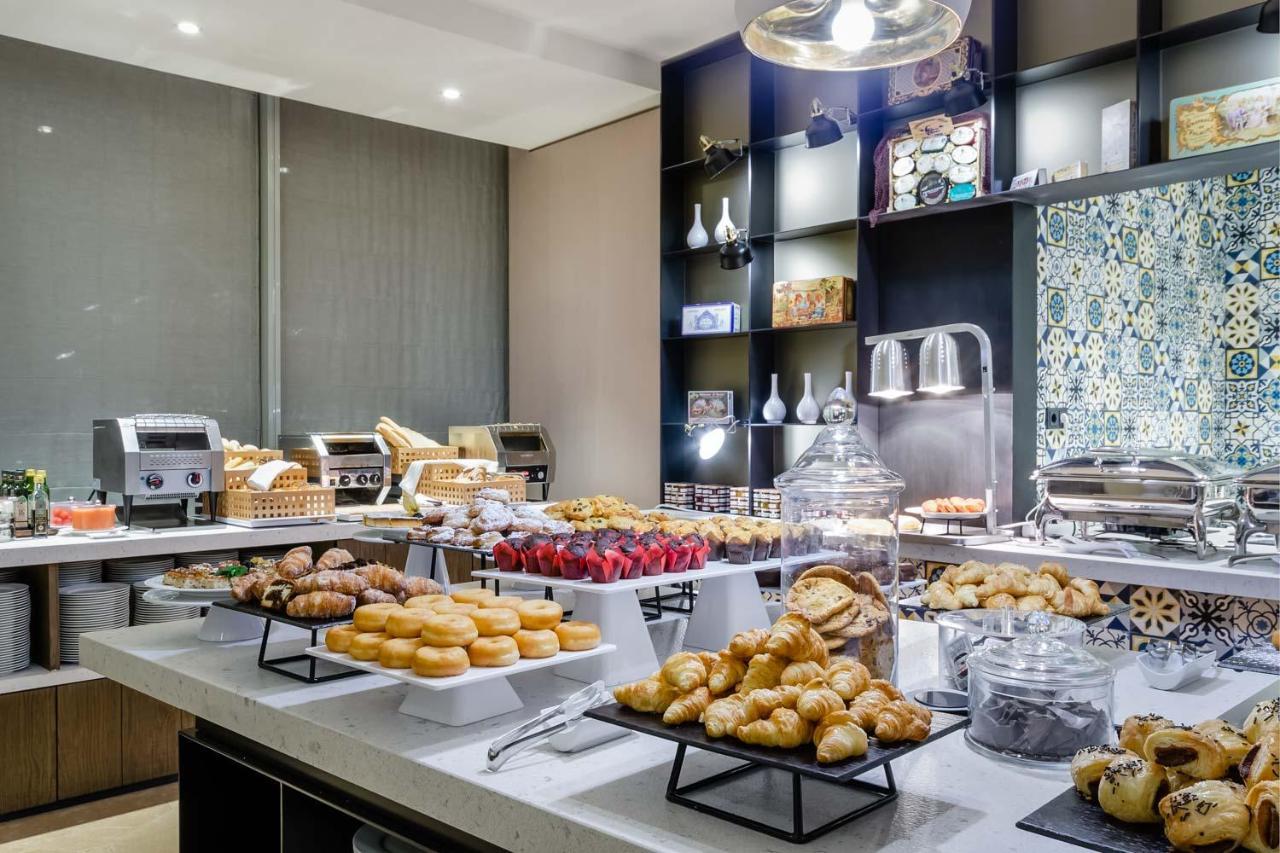 Eurostars Torre Sevilla Esterno foto The photo depicts a buffet-style breakfast setup featuring a variety of baked goods. There are pastries such as croissants, doughnuts, and sweet rolls arranged on tables. Glass containers hold items like muffins, while trays showcase different types 