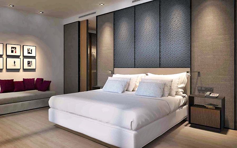 Eurostars Torre Sevilla Esterno foto The photo shows a modern bedroom with a clean and elegant design. The focal point is a large, comfortable bed with white bedding and multiple pillows. Behind the bed, there is a decorative wall panel that adds texture. To the left, there is a minimal