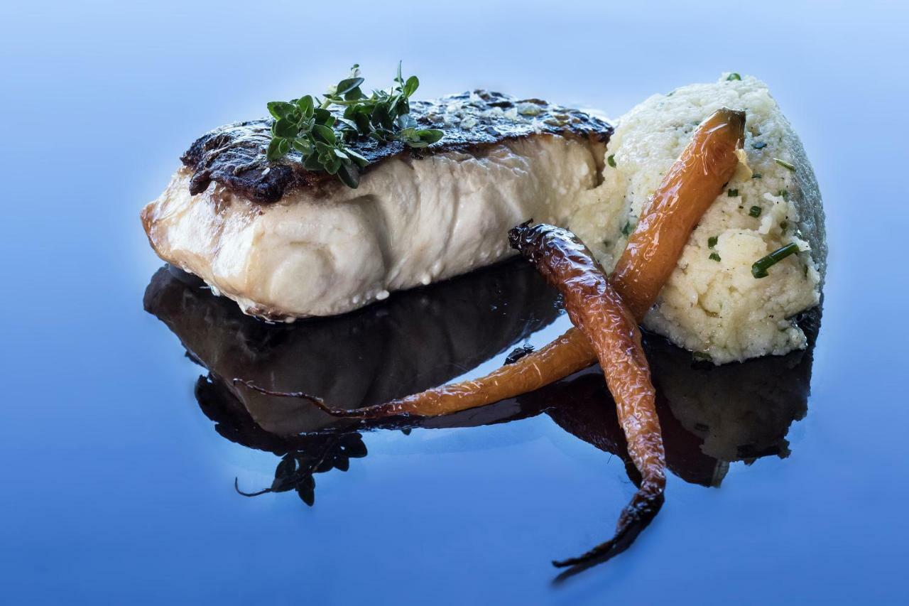 Eurostars Torre Sevilla Esterno foto The photo showcases a beautifully plated dish featuring a piece of cooked fish, likely with a crisp skin and garnished with fresh herbs. Accompanying the fish is a mound of creamy mashed potatoes, which appears to have some herbs mixed in for added f
