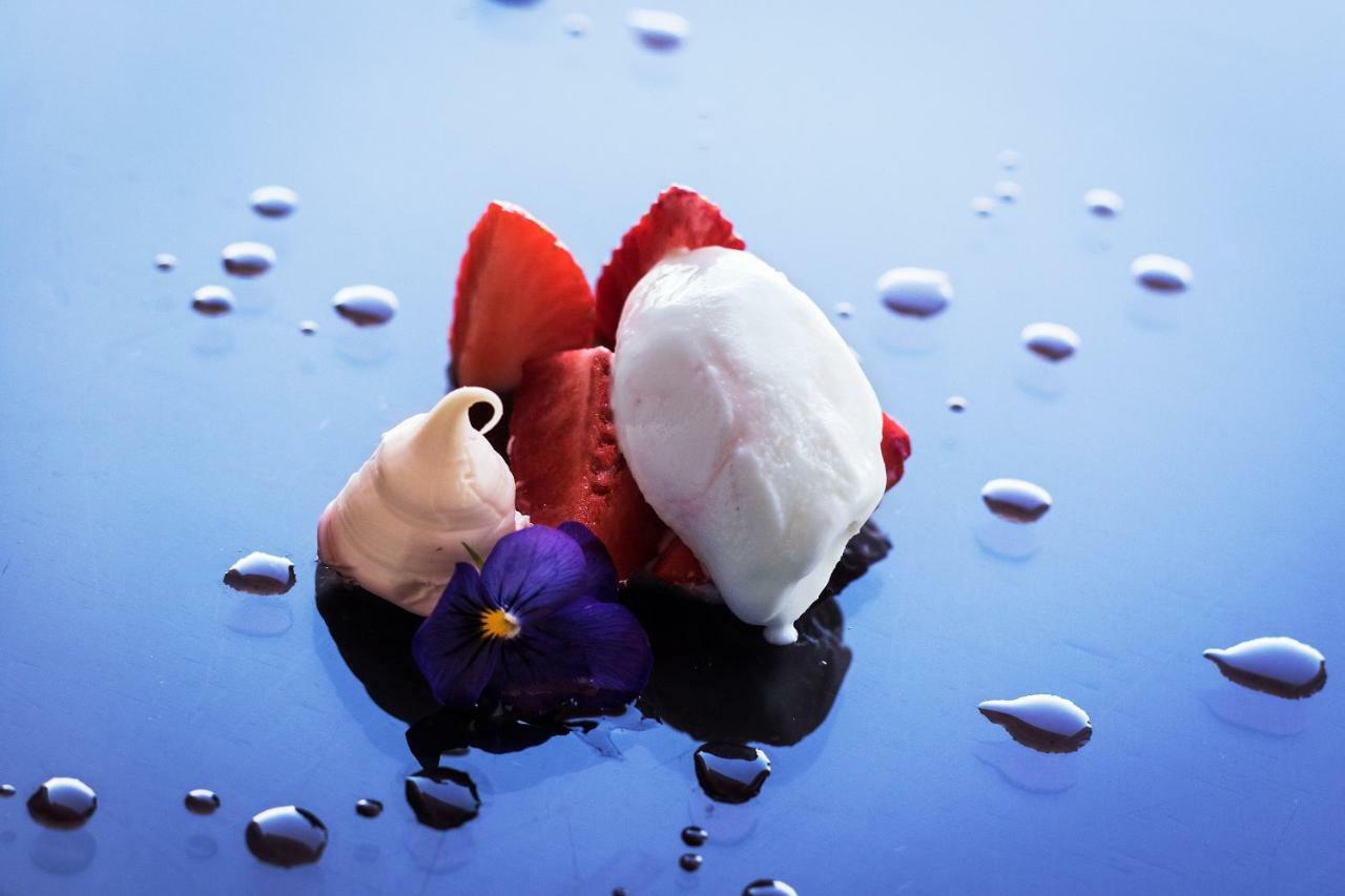 Eurostars Torre Sevilla Esterno foto The photo features an artistic presentation of dessert. It showcases several slices of fresh strawberries arranged neatly, accompanied by dollops of cream or mousse in a light color. Additionally, there is a scoop of what appears to be a light, cream